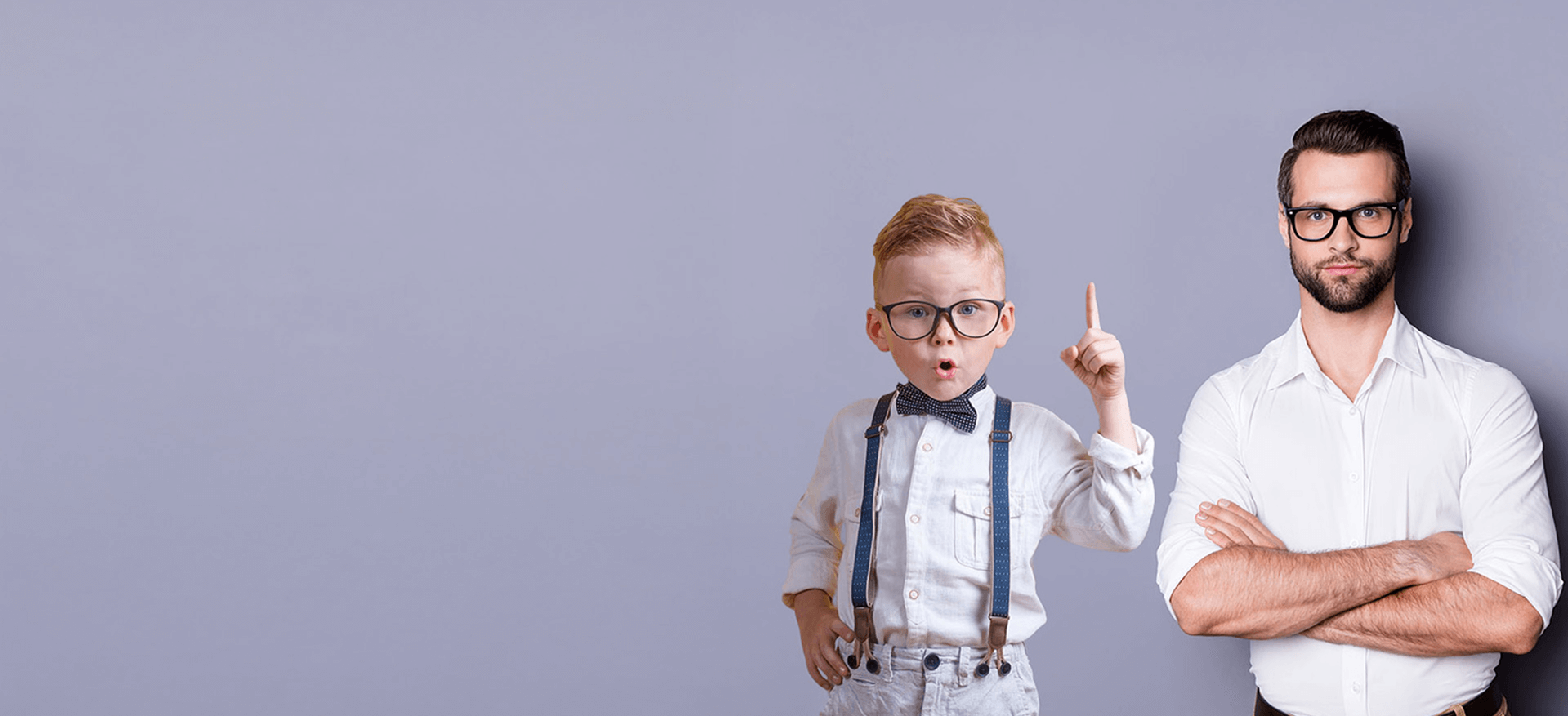 Ein Junge mit Fliege und Hosenträgern steht selbstbewusst neben einem Mann im weißen Hemd vor einem schlichten lila Hintergrund.